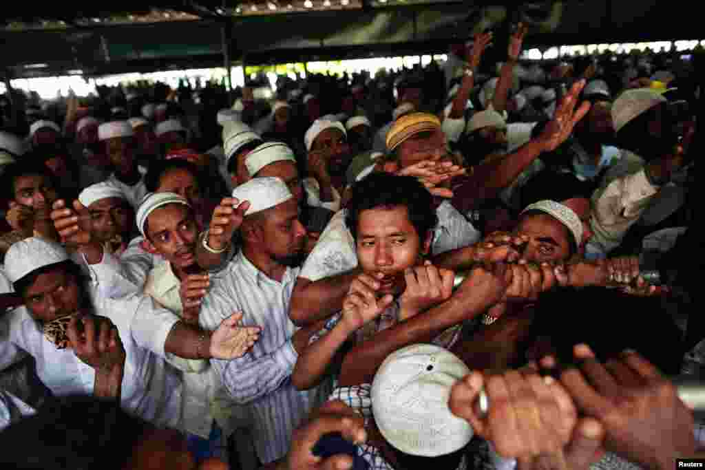 People reach out to help carry the coffin (unseen) of a victim of a fire during a funeral at Yaeway cemetery, Rangoon, Burma, April 2, 2013.