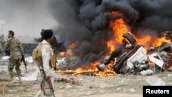 Tentara Syiah yang dikenal dengan sebutan Hashid Shaabi memandangi asap yang mengepul dari kendaraan berpeledak yang dikemudikan pembom bunuh diri ISIS di sebelah selatan Tikrit.