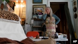 FILE - Nancy Rose, who contracted COVID-19 in 2021 and exhibits long-haul symptoms including brain fog and memory difficulties, pauses while organizing her desk space, Jan. 25, 2022, in Port Jefferson, New York. (AP Photo/John Minchillo, File)