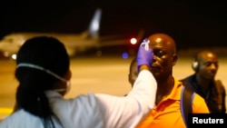 FILE - A health worker checks the temperature of a man arriving at Bata Airport, in Litoral, Equatorial Guinea, Jan. 14, 2015. 