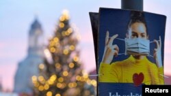 Poster bertuliskan "Aku melindungimu" saat dimulainya pengetatan restriksi untuk mengurangi penyebaran virus Covid-19 di Dresden, Jerman, 14 Desember 2020. REUTERS / Matthias Rietschel