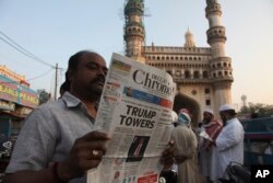 An Indian man reads a newspaper near the Charming monument that has the headline "Trump Towers " to refer to U.S President-elect Donald Trump's victory in Hyderabad, India, Thursday, Nov. 10, 2016.