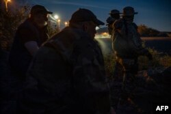 FILE - Members of a militia patrol the U.S.-Mexico border in Sunland Park, New Mexico, March 20, 2019.