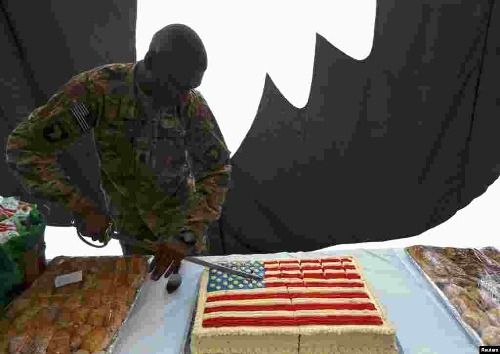 Seorang tentara AS memotong kue berbentuk bendera Amerika dalam perayaan 4 Juli di pangkalan udara Bagram, sebelah utara Kabul, Afghanistan.