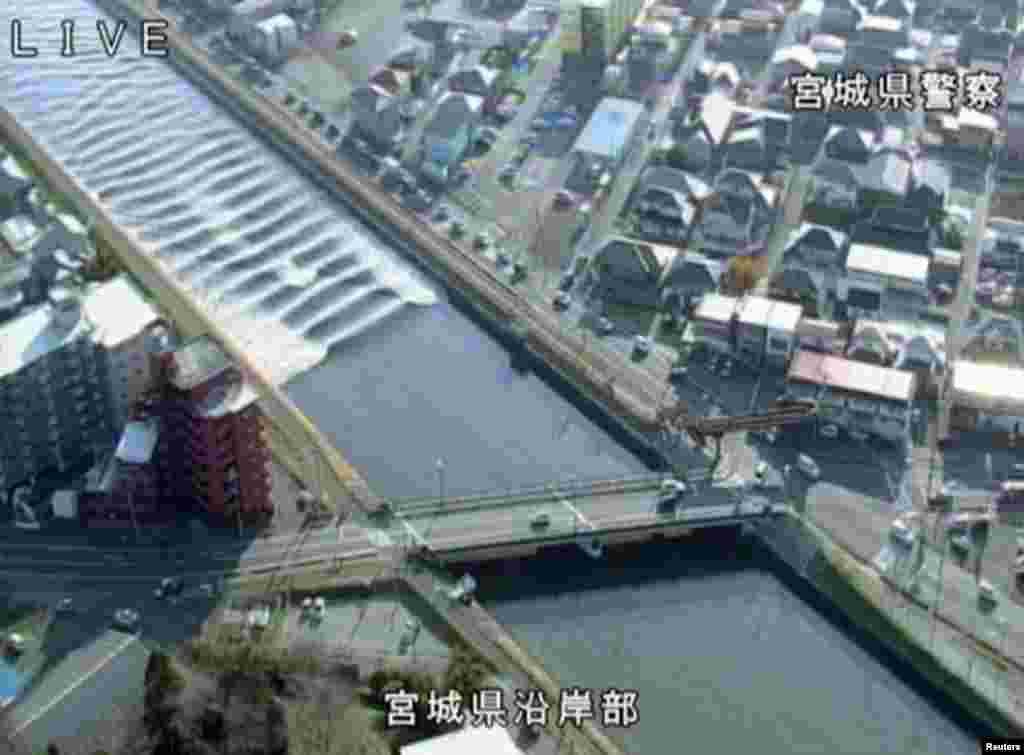 A tidal surge is seen in Sunaoshi River after tsunami advisories were issued following an earthquake in Tagajo, Miyagi prefecture, Japan, in this video grab image released by Miyagi Prefectural Police via Kyodo.