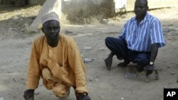 Polio sufferers Yusuf Umar, right, and Aminu Ahmed use wooden blocks to propel themselves through the dusty streets of Kano, Nigeria, November 28, 2008. 