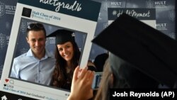 Hult International Business School graduate Victoria Stanciu and her fiance pose as her classmate takes a photo after the graduation ceremony in Boston