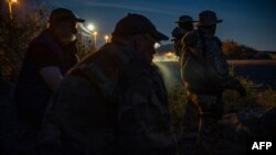 FILE - Members of a militia patrol the U.S.-Mexico border in Sunland Park, New Mexico, March 20, 2019.
