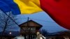 A man waves the Romanian flag outside a voting station after Romania's Constitutional Court annulled the first round of presidential elections, in Mogosoaia, Romania, Dec. 8, 2024. 