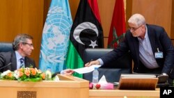 Bernardino Leon, left, the U.N. special envoy to Libya, receives a document from Mustafa Abushagur, a representative of the internationally recognized government that fled to Tobruk, Libya, during a meeting in Skhirate, Morocco, July 2, 2015.