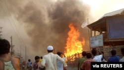 Rohingya refugees watch smoke rising following a fire at the Rohingya refugee camp in Balukhali, southern Bangladesh, March 22, 2021. 