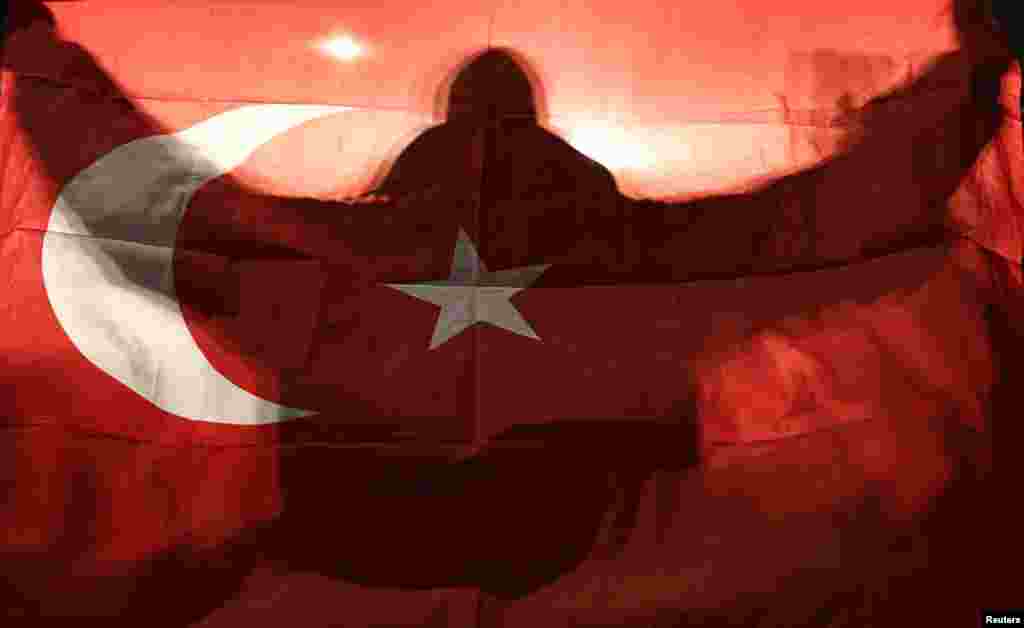 A demonstrator holds a Turkish flag outside the Turkish consulate in Rotterdam where a crowd gathered to await the arrival of the Turkish Family Minister Fatma Betul Sayan Kaya, who traveled to Rotterdam by land after Turkish Foreign Minister Mevlut Cavus