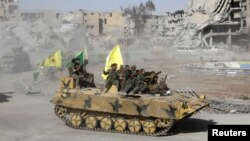 Syrian Democratic Forces (SDF) fighters ride atop of military vehicles as they celebrate victory in Raqqa, Syria, Oct. 17, 2017. (REUTERS/Erik De Castro)
