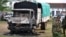 Policemen stand near the wreckage of a burnt vehicle after gunmen attacked outside Gamba police station in Gamba, Kenya, July 6, 2014.