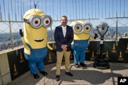 Actor Steve Carell and two Minion characters pose on the 86th floor observatory deck at the Empire State Building to celebrate the upcoming film "Minions: The Rise of Gru" on Tuesday, June 28, 2022, in New York. (Photo by Evan Agostini/Invision/AP)