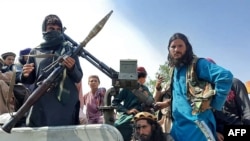 Taliban fighters sit over a vehicle on a street in Laghman province on August 15, 2021. 