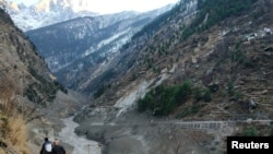 People walk past a destroyed dam after a Himalayan glacier broke and crashed into the dam at Raini Chak Lata village in Chamoli district, northern state of Uttarakhand, India, February 7, 2021. REUTERS/Stringer NO ARCHIVES. NO RESALES.