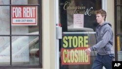 A man walks past a closed business, April 29, 2020, in Chagrin Falls, Ohio. 