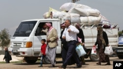 Kurdish refugees, heading home to Kobani, Syria, walk next to a truck full of their belongings en route to a border gate in Suruc,Turkey, but many thousands are reluctant to return to a wasteland of collapsed buildings, April 20, 2015.