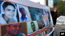 FILE - A woman holds a banner of portraits of Syrian citizens who were prisoners held in Syrian jails, during a sit-in in Beirut, Lebanon, Dec. 6, 2013. 