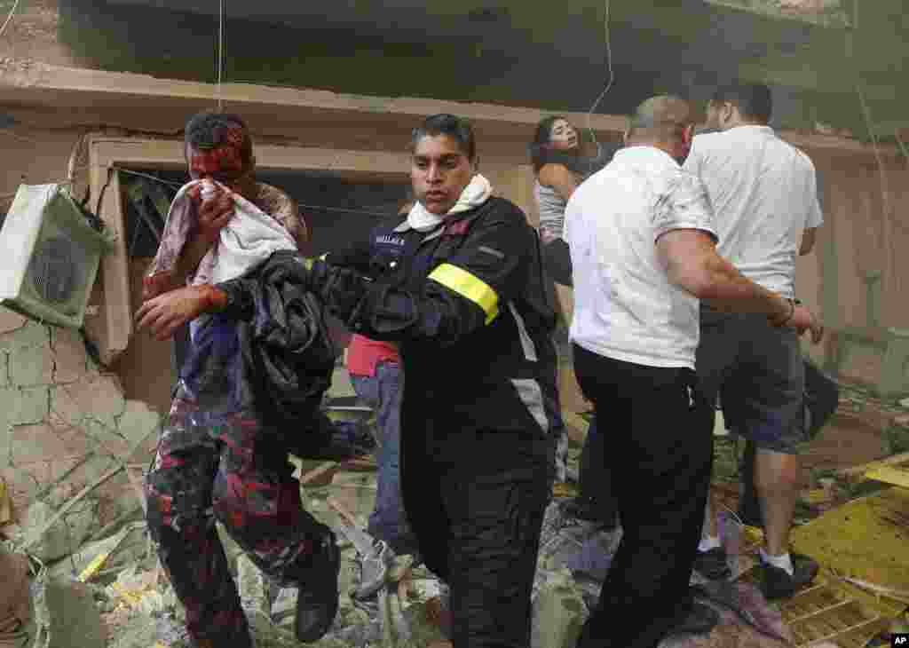 A Lebanese rescue worker, center, helps an wounded man at the scene of an explosion in Beirut, Lebanon, October 19, 2012. 