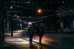 Two young men walk down Main Street under Christmas lights in downtown Farmington, N.H., March 19, 2020.