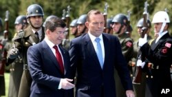 Turkish Prime Minister Ahmet Davutoglu, left, and his Australian counterpart Tony Abbott inspect a military honor guard during a welcome ceremony in Ankara, April 22, 2015.