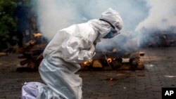 FILE - A woman breaks down as she prays before the cremation of a relative who died of COVID-19 in Gauhati, India, July 2, 2021. India crossed the grim milestone of more than 400,000 people lost to the coronavirus. 