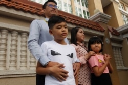 Journalist Yeang Sothearin stands with his family in front of the municipal court, in Phnom Penh, Cambodia, Oct. 3, 2019.