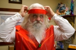 Brad Six adjusts his protective face shield as he prepares to work as Santa Claus at Bass Pro Shops, Friday, Nov. 20, 2020, in Miami. This is Santa Claus in the Coronavirus Age, where visits are done with layers of protection or moved online.