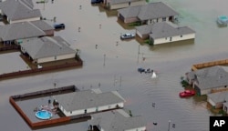 FILE - In this aerial photo, a boat motors between flooded homes after heavy rains inundated Hammond, Louisiana, Aug. 13, 2016.