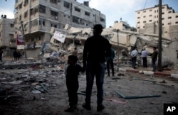 Palestinians stand in front of a destroyed multi-story building was hit by Israeli airstrikes in Gaza City, May 5, 2019.