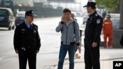 Chinese policemen watch as a man walks near the Beijing No. 3 Intermediate Court in Beijing, April 17, 2015, during the trial of a journalist.