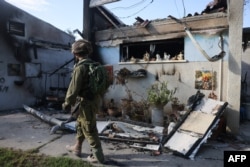 Izraelski vojnik prolazi pored zapaljene kuće 17. oktobra 2023. u blizini granice sa Gazom