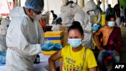 រូបឯកសារ៖ មន្ត្រីសុខាភិបាលក្នុងឯកសណ្ឋានការពារការឆ្លងមេរោគ កំពុងចាក់វ៉ាក់សាំងបង្ការជំងឺកូវីដ១៩ ស៊ីណូហ្វាម (Sinopharm) របស់ចិន ដល់ពលរដ្ឋនៅវត្តមួយកន្លែងក្នុងរាជធានីភ្នំពេញ កាលពីថ្ងៃទី ២០ ខែឧសភា ឆ្នាំ ២០២១។