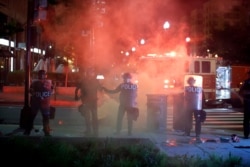 Police in riot gear watch as demonstrators gather to protest the death of George Floyd, May 30, 2020, near the White House in Washington.