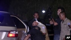 Covered by what looks like a coat, Panama's ex-dictator Manuel Noriega, left, is helped to get out of a car and onto a wheelchair upon his arrival to El Renacer prison in the outskirts of Panama City, Sunday, Dec. 11, 2011.