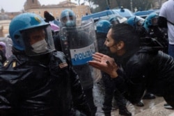A demonstrator gestures as she speaks to a police officer during a protest of restaurant and small-business owners who call for their businesses to be allowed to reopen amid the coronavirus outbreak, in Rome, Italy, April 12, 2021.