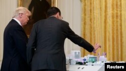 FILE - AT&T CEO Randall Stephenson, right, demonstrates 5G technology to President Donald Trump during the "American Leadership in Emerging Technology" event in the East Room of the White House, June 22, 2017, in Washington. 