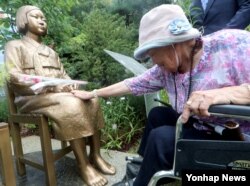 11일 경기도 광명시 광명동굴에서 열린 '평화를 위한 소녀의 꽃밭 조성 협약식'에 참석한 일본군 '위안부' 피해자 이옥선(91) 할머니가 비에 젖은 소녀상을 어루만지고 있다.