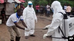 FILE - Health workers wash their hands after taking a blood specimen from a child to test for the Ebola virus in an area where a 17-year old boy died from the virus on the outskirts of Monrovia, Liberia, June 30, 2015. 