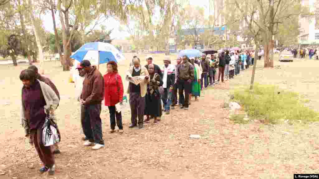 A Kenyan voter catches up with the day&#39;s news as he waits in line with others to cast his ballot. (L. Ruvaga/VOA)