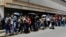 FILE - People queue up to try to buy basic food items outside a supermarket in Caracas, Venezuela, April 28, 2016. 