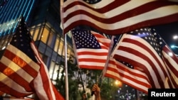 Demonstran anti-pemerintah memegang bendera AS ketika mereka berbaris dalam protes menentang permohonan hukum darurat di Hong Kong, Cina, 14 Oktober 2019. (Foto: Reuters / Ammar Awad)