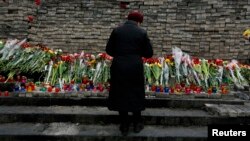 FILE - A woman mourns before a memorial to those killed in violence in Kyiv, Feb. 25, 2014 — the day that parliament voted to send fugitive President Viktor Yanukovich to be tried by the International Criminal Court for "serious crimes."