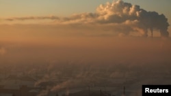 FILE - Power plant chimneys stand behind a coal burning neighborhood covered in a thick haze on the outskirts of Ulaanbaatar, Mongolia, Jan. 19, 2017.
