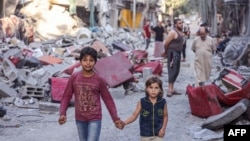 ក្មេងប្រុសស្រីប៉ាឡេស្ទីន​ដើរ​កាន់ដៃ​គ្នា​កាត់​អគារ​ដែល​ត្រូវ​បាន​បំផ្លាញ បន្ទាប់ពី​ការទម្លាក់​គ្រាប់​បែក​របស់​អ៊ីស្រាអែល​លើ​ជំរំ​ជនភៀសខ្លួន Nuseirat នៅ​កណ្តាល​តំបន់​ហ្កាហ្សា នៅ​ថ្ងៃទី៣០ ខែតុលា ឆ្នាំ​២០២៣ ចំ​ពេល​មាន​ការប្រយុទ្ធ​គ្នា​រវាង​អ៊ីស្រាអែល និង​ក្រុម​ហាម៉ាស់​ប៉ាឡេស្ទីន។