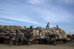 FILE - Workers illegally distribute old computers and printers to others for future recycling outside the government designated recycling center, at the township of Guiyu in China's southern Guangdong province, June 8, 2015.