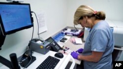 FILE - Stephanie Richurk, a nurse at the University of Pittsburgh Medical Center, sorts blood samples collected from participants in the "All of Us" research program in Pittsburgh, Aug. 7, 2017. On Sunday, the U.S. government will open nationwide enrollment for an ambitious experiment: If they can build a large enough database comparing the genetics, lifestyles and environments of people from all walks of life, researchers hope to learn why some escape illness and others don’t, and better customize ways to prevent and treat disease.