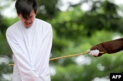 FILE - One of two Indonesian men is publicly caned for having sex, in a first for the Muslim-majority country where there are concerns over mounting hostility towards the small gay community, in Banda Aceh, May 23, 2017.